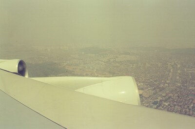 The hazy city sprawl beyond the aircraft wing — Seoul, in transit (20-25 May 2000)