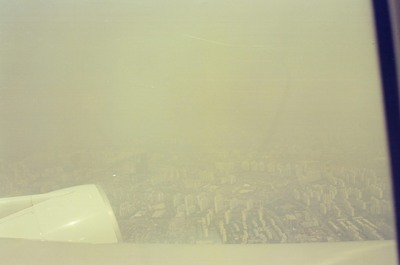 A smoggy cityscape of apartment blocks from above — Seoul, in transit (20-25 May 2000)