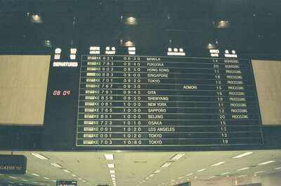 The airport departures board listing morning flights — Seoul, in transit (20-25 May 2000)