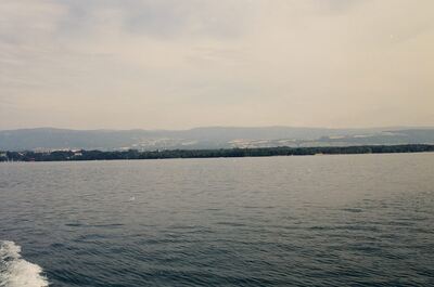 Wooded shoreline and hills across Lake Geneva — Geneva, Switzerland (1 July 2000)