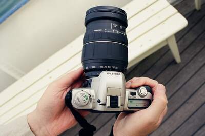 A Pentax camera with zoom lens held over a deck — Geneva, Switzerland (1 July 2000)