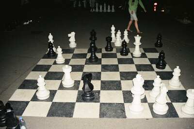 Players around a giant chess set at night — Geneva, Switzerland (1 July 2000)
