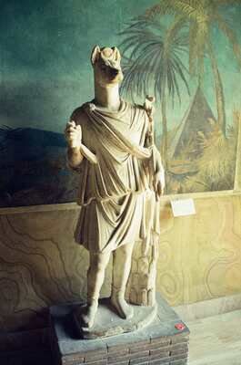 A headless draped classical marble statue against a green wall — Vatican Museums, Vatican City (21-27 May 2000)