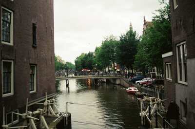 A small bridge over a narrow canal between brick houses — Amsterdam, The Netherlands (19-26 June 2000)