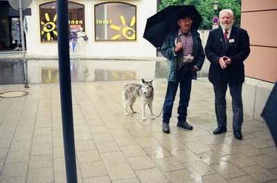 A man with a husky and a guide outside a village shop — Oberammergau, Germany (19-26 June 2000)
