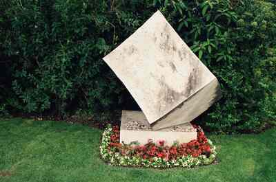 A modern tilted-stone grave monument ringed with red flowers — Vienna, Austria (14-16 June 2000)