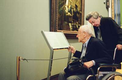 An elderly man in a wheelchair reading a gallery information panel — Vienna, Austria (16-18 June 2000)