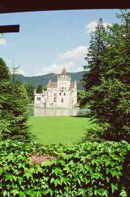 A turreted lakeside villa framed by green foliage — Salzkammergut, Austria (16-18 June 2000)