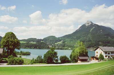 An alpine lake below a steep peak with a farmhouse nearby — Salzkammergut, Austria (16-18 June 2000)