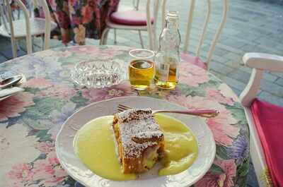 An apple strudel with vanilla sauce on a floral cafe table — Salzburg, Austria (16-18 June 2000)