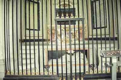 A barred side chapel altar with a recumbent effigy — Rome, Italy (late May 2000)