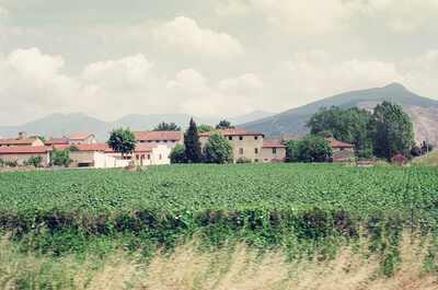 Farmhouses and a green field below hazy mountains — Tuscany, Italy (26-27 May 2000)
