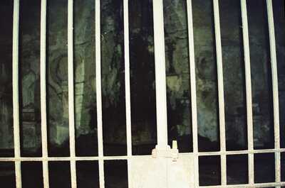 A barred gate guarding a dim ruined interior — Rome, Italy (21-27 May 2000)
