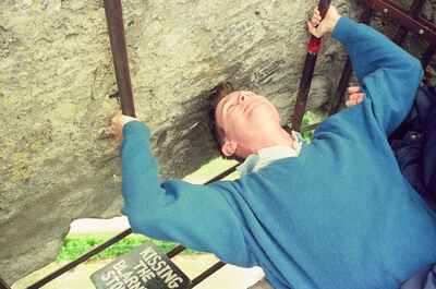 A man leaning back to kiss the Blarney Stone — Cork, Ireland (4-9 July 2000)
