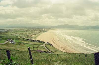 A long curving sandy strand seen from grassy clifftop — Dingle Peninsula, Ireland (4-9 July 2000)