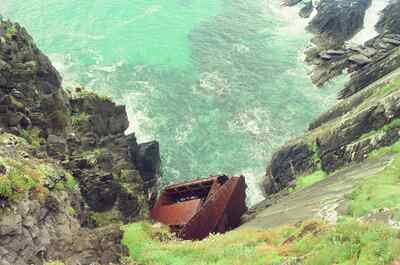 A rusting shipwreck wedged in a rocky cove below cliffs — Dingle Peninsula, Ireland (4-9 July 2000)