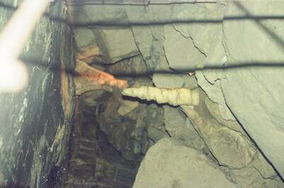 A pale stalactite jutting from dark cave rock — Ireland, Ireland (4-9 July 2000)