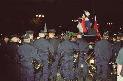 A line of CRS police facing flag-waving celebrants at night — Paris, France (2-8 July 2000)