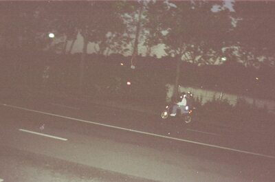 Two riders on a scooter along a dark roadside at night — Paris, France (2-8 July 2000)