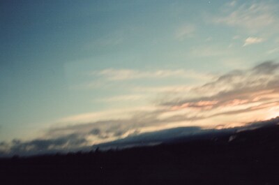A pink-streaked sunset sky over dark hills — Scotland, Scotland (August 2000)