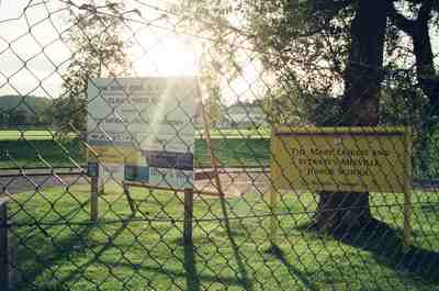 School noticeboards behind a chain-link fence at dusk — Edinburgh, Scotland (August 2000)