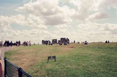 Stonehenge across the field beyond a low fence — Stonehenge, England (mid-August 2000)