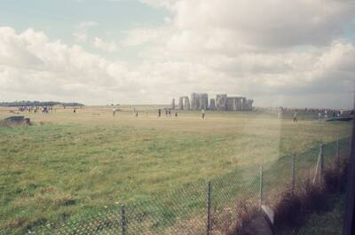 Stonehenge seen across the field from behind a fence — Stonehenge, England (mid-August 2000)