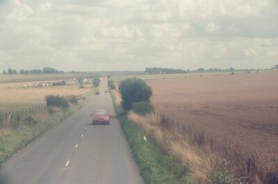 A red car on a straight rural road past Stonehenge — Stonehenge, England (mid-August 2000)