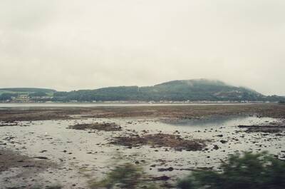 A mist-capped headland above a firth at low tide — Scottish Highlands, Scotland (late July 2000)