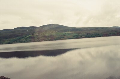 A rounded peak mirrored in the glassy loch surface — Scottish Highlands, Scotland (late July 2000)