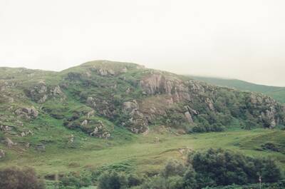 A craggy rock-strewn hillside above grassy moorland — Scottish Highlands, Scotland (late July 2000)