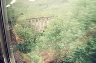 The arches of the Glenfinnan Viaduct through trackside trees — Glenfinnan, Scotland (late July 2000)