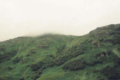 A mist-shrouded green hillside dotted with rocky outcrops — Scottish Highlands, Scotland (late July 2000)