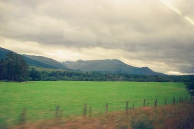 Mountains rising beyond a bright green Highland meadow — Scottish Highlands, Scotland (August 2000)
