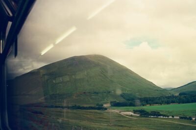 A smooth green mountain rising beyond a Highland glen — Scottish Highlands, Scotland (August 2000)
