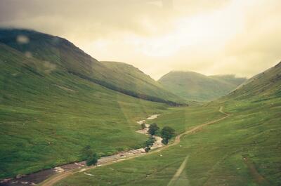 A stream winding through a deep green mountain glen — Scottish Highlands, Scotland (August 2000)