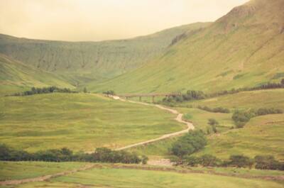 A viaduct and track snaking through a broad green glen — Scottish Highlands, Scotland (August 2000)