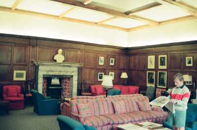 Ian reading a newspaper in a panelled common room — Oxford, England (August 2000)