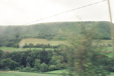 A green hillside and farmland blurred from a train — rural Wales, Wales (August 2000)