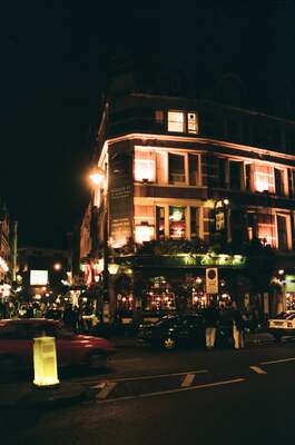 A brightly lit pub on a West End street at night — London, England (August 2000)
