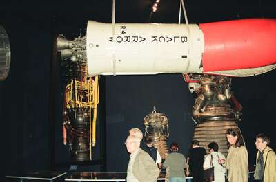 Visitors beside towering rocket engines on display — London, England (August 2000)