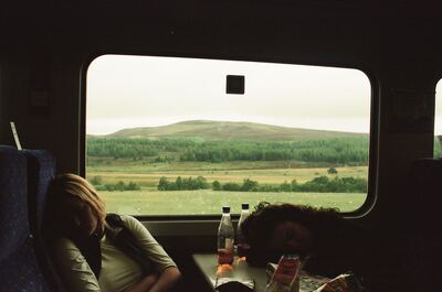 Two passengers dozing by a train window over moorland — Scottish Highlands, Scotland (late July - early August 2000)