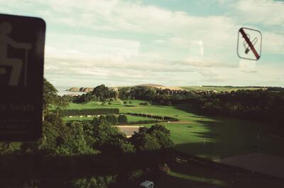 Green parkland and distant coast past train window signs — Stonehaven area coast, Scotland (late July - early August 2000)