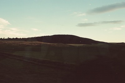 A wooded hill at dusk with a crescent moon above — Aberdeen, Scotland (late July - early August 2000)