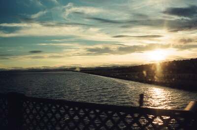 Sun setting over the sea beyond a lattice fence — Aberdeen, Scotland (late July - early August 2000)