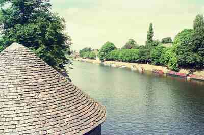 A weathered conical roof above the tree-lined River Ouse — Canterbury, England (mid-August 2000)