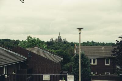 A distant spired building beyond suburban rooftops — Edinburgh, Scotland (August 2000)