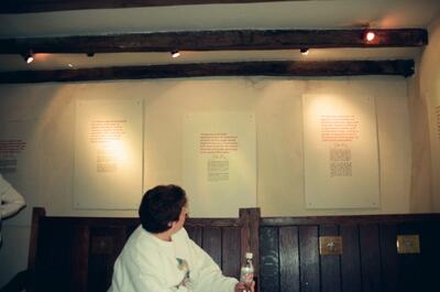 A woman seated below framed texts in John Knox House — Edinburgh, Scotland (August 2000)