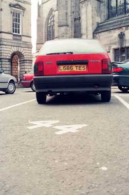 A red car parked on the Royal Mile — Edinburgh, Scotland (August 2000)
