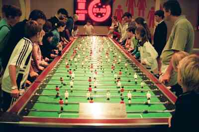 Crowds at a long row of foosball tables — London, England (August 2000)